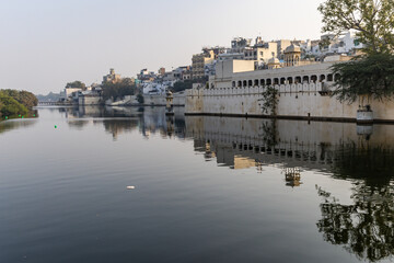 Fototapeta premium Tranquil Waterfront View of Udaipur Cityscape with Historic Architecture and Reflections
