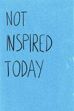 Handwritten message on blue paper conveying feeling of being uninspired