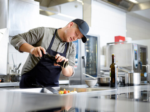 Chef adding pepper on meal in kitchen at restaurant