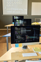 Vertical image of modern IT classroom with computers on desks