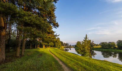 A path runs along a river with trees on either side