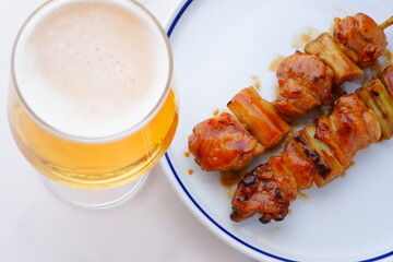炭火焼の焼き鳥（タレ）とビールのグラス