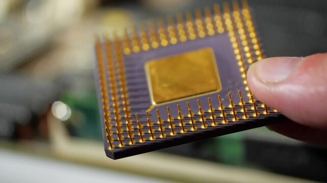 vintage computer microprocessor is held by a man's hand on a background of computer equipment
