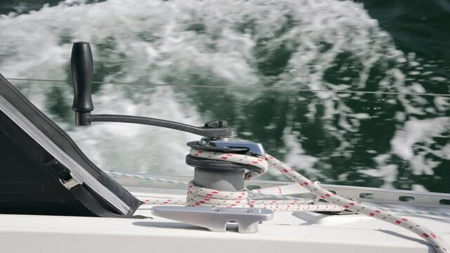 Stock film of sailboat with genua fore sail, rope, winch with red and white rope, sheet,  or line on deck of sailing boat through high winds at sea, flowing water