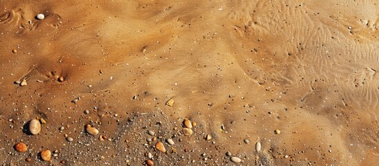 Brown sandy beach with small stones creating a textured background ideal for use as a copy space...