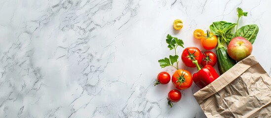 Fresh fruits and vegetables in a paper bag showcased on a white marble backdrop in a flat lay style perfect for adding text to the copy space image