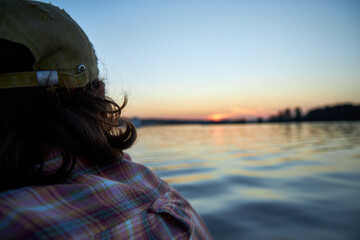 a man driving a boat on the river in the evening at sunset