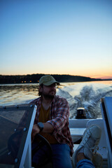 a man driving a boat on the river in the evening at sunset