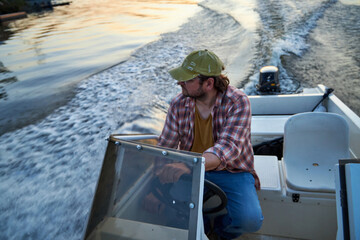 a man driving a boat on the river in the evening at sunset