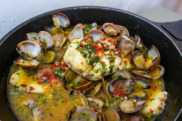Delicious Alentejo-style dogfish with clams, featuring tender fish and savory clams in a rich, flavorful sauce, served with fresh herbs and a sprinkle of paprika.