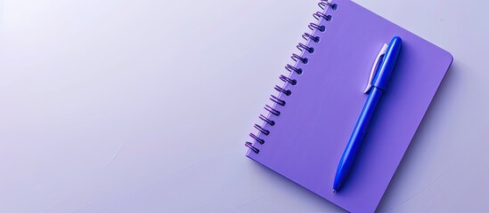 Purple notebook and blue pen viewed from above on a white background making it suitable for school or office themed wallpapers with a flat lay composition and ample copy space image