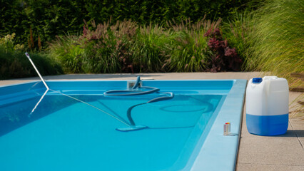 Pool cleaning hose and vacuum head with a large chemical container and water testing kit on the...