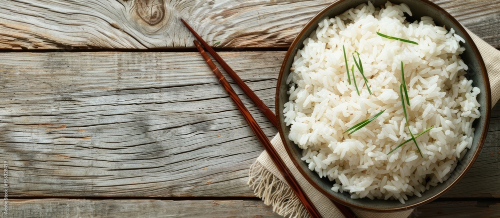 Fototapete A delicious bowl of cooked rice with chopsticks on a wooden table suitable for adding text in the empty area of the image. Creative banner. Copyspace image