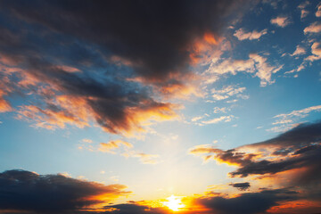 Sunrise or sundown sky with soft clouds and sunbeams. Serene sunset with colorful clouds. Sky is a mix of blue and orange, creating a warm and peaceful atmosphere