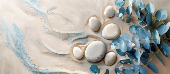 Minimalistic background with round rock stones blue eucalyptus branches and beige sand ideal for...