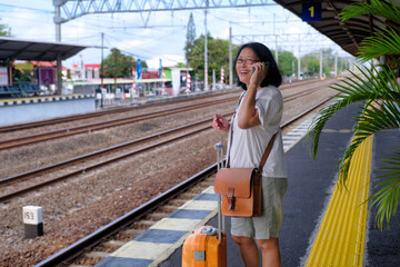 Woman standing on a railway platform, waiting for her train to arrive © Simon