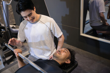 Obraz premium Personal trainer teaching bench press with a smile at a training gym.