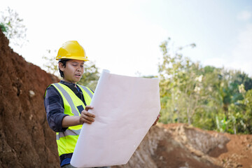 young male construction worker carrying blueprints, reading and analyzing them