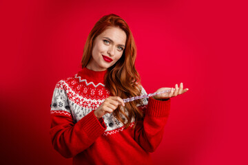 Photo of young satisfied confident lady wearing festive ugly sweater holding christmas tree icicle toy holiday isolated on red color background