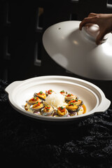Abalone delicacy in a bowl with lid open, black background, indoor shot