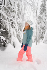 A girl in a bright winter coat, playing in a snowy forest, perfect for promoting family-friendly winter vacations, seasonal clothing, or outdoor winter sports.