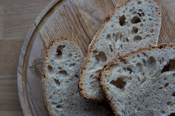 Slices of homemade organic sourdough bread on a circular wooden chopping board