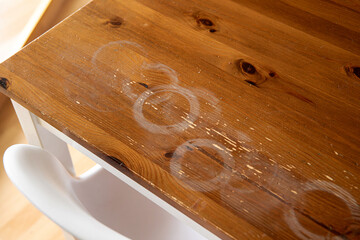 Ugly white round heat stains on home kitchen table, wood furniture ruined indoors home.