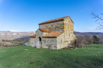 Obraz premium Mother of God church of Chachubeti village. Multicolored stones in the wall. Green grass. Mountains and hills in the background
