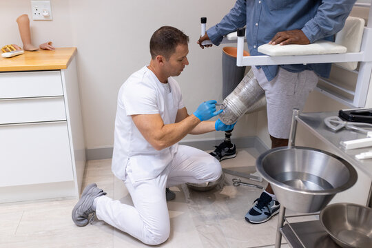 Technician adjusting prosthetic leg for patient in medical lab, ensuring proper fit