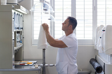 Technician in prosthetic lab adjusting equipment for creating artificial limbs