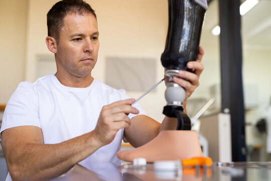 Technician adjusting prosthetic leg in lab, focusing on precise alignment