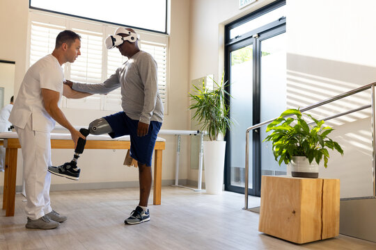 Therapist assisting man with prosthetic leg using VR headset in rehabilitation
