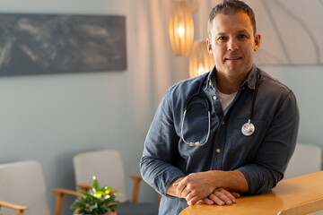 Smiling confidently, doctor with stethoscope standing in medical office, copy space