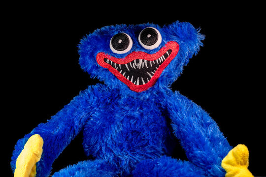 Huggy Wuggy from the Poppy Playtime sits in the dark room