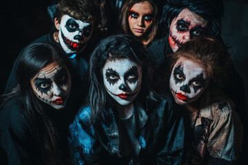 Group of friends with scary halloween makeup posing together in the dark