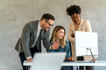 Group of multiethnic business people analyzing data using computer while working in the office