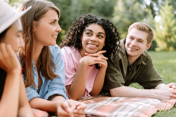 Cheerful smiling multiracial friends talking, communication, meeting in green park