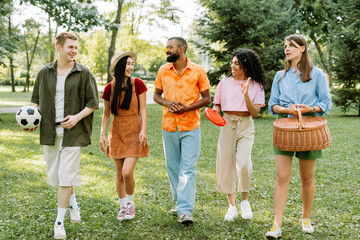 Group of young people walking and talking on grass in park