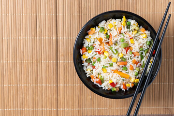 White fried rice with vegetables on wooden table. Top view. Copy space