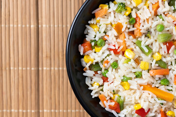 White fried rice with vegetables on wooden table. Top view. Copy space