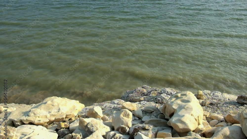 Poster the gentle movement of the waves on the edge of the lake. the edge of the lake with a limestone stru