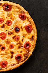 Pie Quiche Lorraine with tomatoes and melted cheese on the table close-up. Copy space.