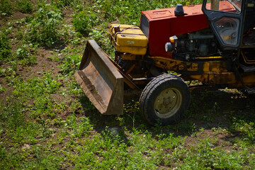 A powerful bulldozer clears a field of tall grass, preparing the land for a new construction project. A concept for building, engineering and transforming the countryside.