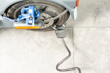 Electric scooter is secured with a lock. Close-up of a scooter and bicycle lock.