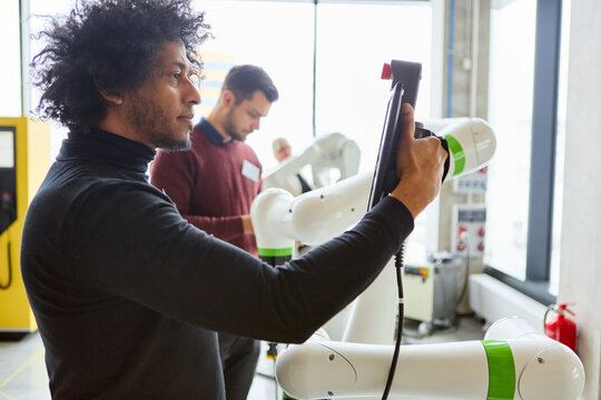 Engineers programming robots with gripper arms for industrial automation