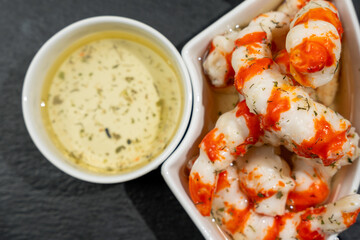 Bowl with Surimi in the form of shrimps on a black stone.