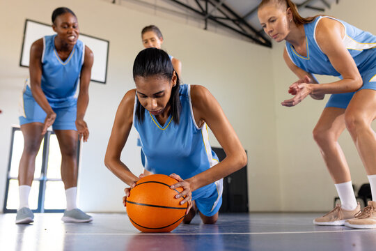 Playing basketball, female team encouraging teammate doing push-ups with ball - Powered by Adobe