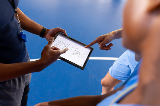 Basketball male coach using tablet to discuss game strategy with players