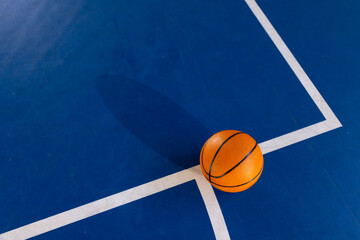 Fototapeta premium Basketball on court, resting on blue floor with white lines, copy space