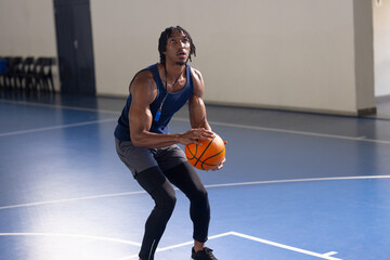 Playing basketball, man preparing to shoot ball on indoor court